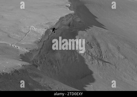 Vista dall'alto di uno snowboarder senza paura che salta sopra la formazione rocciosa su un paesaggio innevato durante le vacanze invernali in Canada Foto Stock