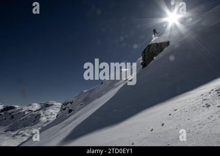 Dal basso, potrai ammirare lo snowboarder senza paura che salta sopra la formazione rocciosa su un paesaggio innevato durante le vacanze invernali in Canada Foto Stock