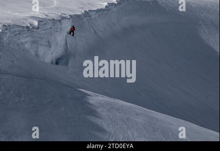 Vista dall'alto di uno snowboarder senza paura che salta sopra la formazione rocciosa su un paesaggio innevato durante le vacanze invernali in Canada Foto Stock