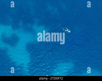 Un colpo aereo cattura una sola persona che galleggia pacificamente nelle acque azzurre e trasparenti del Mar Mediterraneo lungo la Côte costa azzurra vicino a Nizza, Foto Stock