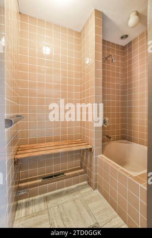 Panca vuota in legno accanto a vasca e cabina doccia con pareti piastrellate nel moderno bagno di casa Foto Stock