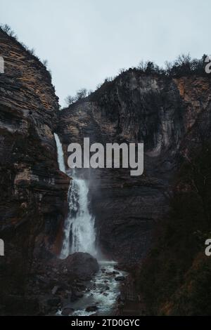 Una maestosa cascata scende dalle aspre scogliere in un letto roccioso del Parco Nazionale di Ordesa, situato nella catena montuosa dei Pirenei Foto Stock