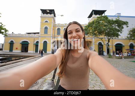 Sorridente scatta selfie davanti al mercato pubblico di Florianopolis, Santa Catarina, Brasile Foto Stock