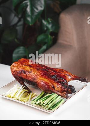 Anatra arrostita al forno - anatra intera al forno con cetriolo verde fresco e cipolla. Anatra di Pechino intera sul tavolo del ristorante. L'anatra di Pechino è un piatto tradizionale cinese Foto Stock