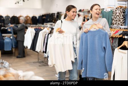 Due donne che scelgono un maglione comodo nel negozio di abbigliamento Foto Stock