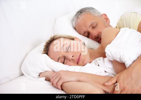Coppia affamata, stanca e matura che dorme a letto per coccolarsi insieme il fine settimana mattina a casa. Calmo, pacifico e uomo e donna che fanno un pisolino e.. Foto Stock