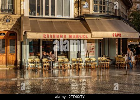 La luce del sole si riflette sulla strada bagnata di fronte al Café Etienne Marcel, una brasserie, un caffè al 34 di Rue Étienne Marcel nel 2° arrondissement di Parigi Foto Stock