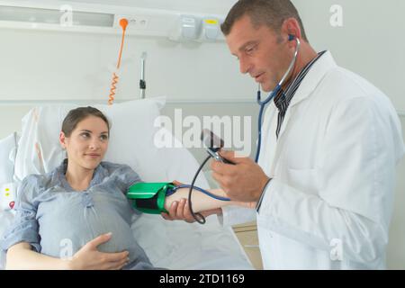 medico che misura la pressione sanguigna di una donna incinta Foto Stock