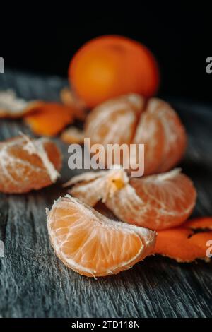 alcune arance mandarine sbucciate su un tavolo di legno rustico grigio Foto Stock