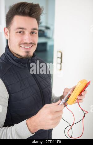 happy electrician controlla il dispositivo per verificare la presenza di prese di corrente elettriche Foto Stock