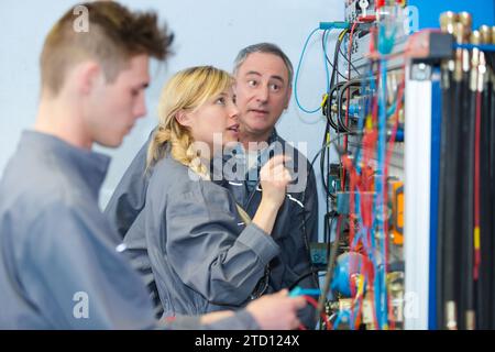 Insegnante osservando gli studenti al lavoro su circuiti elettrici Foto Stock