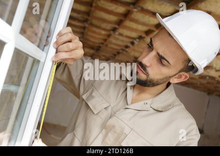 operaio edile che installa nuove finestre in casa Foto Stock