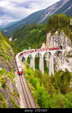 Treno rosso svizzero sul viadotto in montagna per un giro panoramico Foto Stock