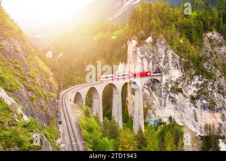 Treno rosso svizzero sul viadotto in montagna per un giro panoramico Foto Stock