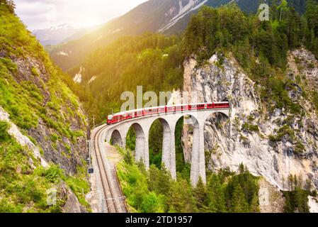 Treno rosso svizzero sul viadotto in montagna per un giro panoramico Foto Stock