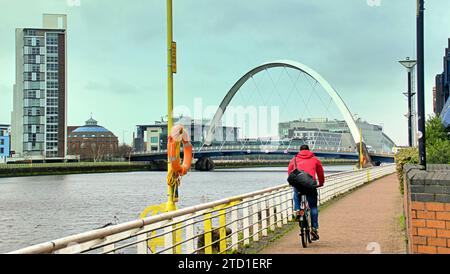 Glasgow, Scozia, Regno Unito. 15 dicembre 2023. Tempo nel Regno Unito: Nuvoloso ha visto una giornata miserabile e bagnata nel centro della città. Come ciclista pedala lungo la passerella clyde vicino al ponte scoiattico . Credit Gerard Ferry/Alamy Live News Foto Stock