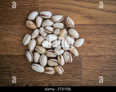 Vista dall'alto dei dadi di pistacchio salati su un tavolo di legno, un gran numero di pistacchi salati e croccanti da vicino Foto Stock