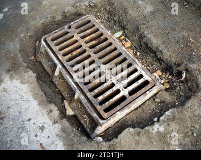 Griglia di drenaggio in ghisa per tempeste su una strada in fase di riparazione Foto Stock