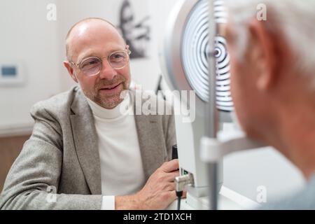 L'optometrista sorride al paziente durante l'esame oculare con cheratografo in primo piano Foto Stock