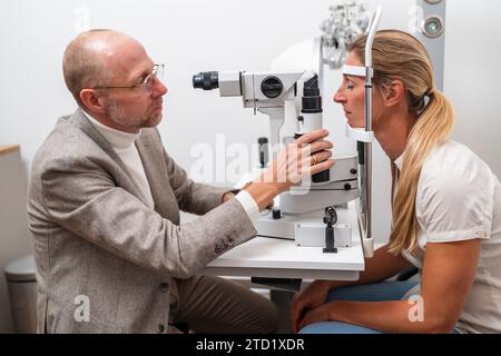 Optometrista che esegue un esame oculare utilizzando una lampada a fessura su una paziente in clinica. Foto in primo piano. Concetto di sanità e medicina Foto Stock