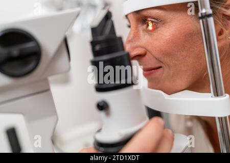 Donna sottoposta a un esame oculare con particolare attenzione al suo occhio illuminato utilizzando una lampada a fessura presso la clinica oftalmologica. Foto in primo piano. Assistenza sanitaria e. Foto Stock