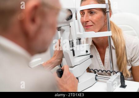 L'optometrista è sottoposta a un esame oculistico con particolare attenzione al suo occhio illuminato utilizzando una lampada a fessura presso la clinica. Foto in primo piano. Assistenza sanitaria Foto Stock