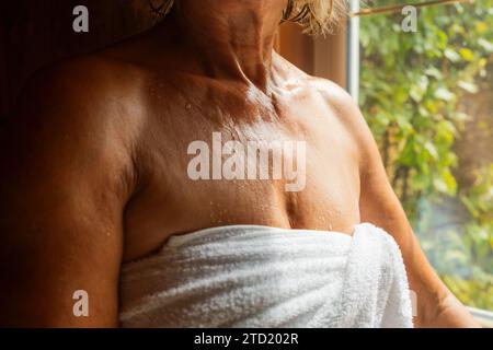 Primo piano della spalla della donna nella sauna, goccioline di sudore visibili, asciugamano avvolto. Concetto di hotel Spa e benessere Foto Stock