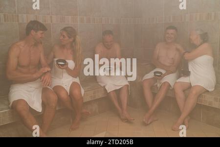 Persone in un bagno turco con sale, conversazione e relax in un hotel benessere con spa Foto Stock