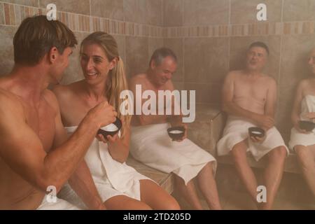 Persone che si impegnano in una macchia di sale in un bagno turco, conversano e si godono momenti in un hotel benessere con centro benessere Foto Stock