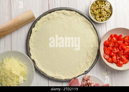 Vari componenti della pizza che circondano la base dell'impasto della pizza Foto Stock