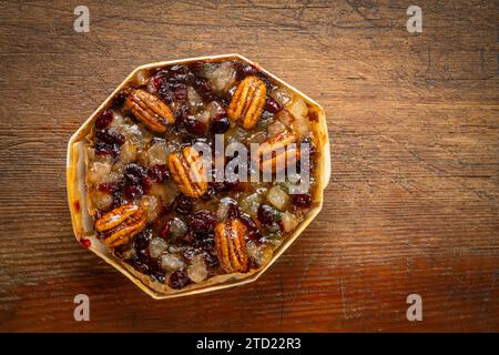 torta al rum con noci pecan, ananas, ciliegie secche e mirtilli rossi contro legno rustico Foto Stock