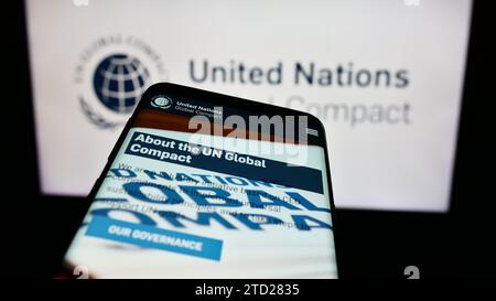 Smartphone con sito Web del Patto delle Nazioni Unite Global Compact davanti al logo. Mettere a fuoco in alto a sinistra sul display del telefono. Foto Stock