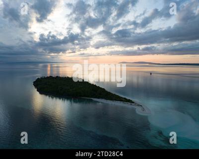 L'alba illumina la remota isola di Koon vicino a Seram, Indonesia. Le barriere coralline di quest'isola, e i mari circostanti, supportano un'elevata biodiversità marina. Foto Stock