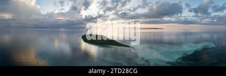 L'alba illumina la remota isola di Koon vicino a Seram, Indonesia. Le barriere coralline di quest'isola, e i mari circostanti, supportano un'elevata biodiversità marina. Foto Stock