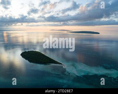 L'alba illumina la remota isola di Koon vicino a Seram, Indonesia. Le barriere coralline di quest'isola, e i mari circostanti, supportano un'elevata biodiversità marina. Foto Stock