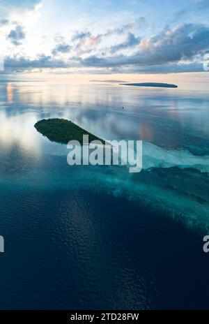 L'alba illumina la remota isola di Koon vicino a Seram, Indonesia. Le barriere coralline di quest'isola, e i mari circostanti, supportano un'elevata biodiversità marina. Foto Stock