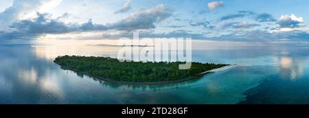 L'alba illumina la remota isola di Koon vicino a Seram, Indonesia. Le barriere coralline di quest'isola, e i mari circostanti, supportano un'elevata biodiversità marina. Foto Stock