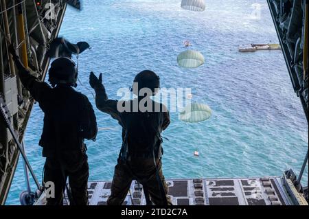 Lukunor, Isole Mortlock, Stati Federati di Micronesia. 3 dicembre 2023. I caricatori dell'aeronautica militare statunitense Senior Airman John Douglas e Senior Airman Ian Munoz guardano i pacchi di carico umanitario galleggiare su una laguna con il paracadute di un C-130J Super Hercules dell'aeronautica militare statunitense durante l'operazione Christmas Drop, il 3 dicembre 2023 a Lukunor, Isole Mortlock, Micronesia. L'operazione Christmas Drop è la più antica missione umanitaria e di soccorso in caso di catastrofi, che fornisce 71.000 libbre di cibo, regali e provviste per assistere le remote comunità insulari nel Sud del Pacifico. Credito: SRA Brooklyn Golightly/US Airforce pH Foto Stock