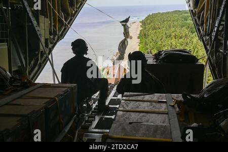 NAMA, Isole Mortlock superiori, Stati Federati di Micronesia. 4 dicembre 2023. SSgt. Dei caricatori dell'aeronautica militare statunitense. Matthew Muravez e il Senior Airman Megan Irvin, lanciano pacchetti umanitari in paracadute in una laguna da un aereo US Air Force C-130J Super Hercules, durante l'operazione Christmas Drop, il 4 dicembre 2023 a Nama, Isole Orientali, Micronesia. L'operazione Christmas Drop è la più antica missione umanitaria e di soccorso in caso di catastrofi, che fornisce 71.000 libbre di cibo, regali e provviste per assistere le remote comunità insulari nel Sud del Pacifico. Credito: SRA Allison Martin/US Airforce Photo/Alamy li Foto Stock