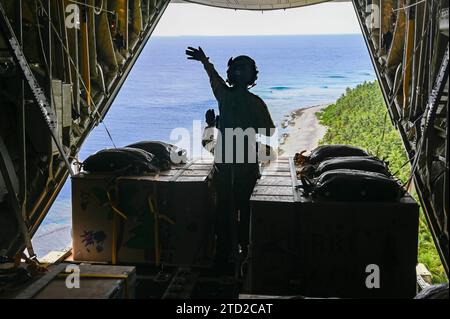 NAMA, Isole Mortlock superiori, Stati Federati di Micronesia. 4 dicembre 2023. SSgt. Dei caricatori dell'aeronautica militare statunitense. Matthew Muravez e il Senior Airman Megan Irvin, lanciano pacchi umanitari in paracadute in una laguna da un aereo US Air Force C-130J Super Hercules, durante l'operazione Christmas Drop, il 4 dicembre 2023 a Nama, Isole Orientali, Micronesia. L'operazione Christmas Drop è la più antica missione umanitaria e di soccorso in caso di catastrofi, che fornisce 71.000 libbre di cibo, regali e provviste per assistere le remote comunità insulari nel Sud del Pacifico. Credito: SRA Allison Martin/US Airforce P. Foto Stock