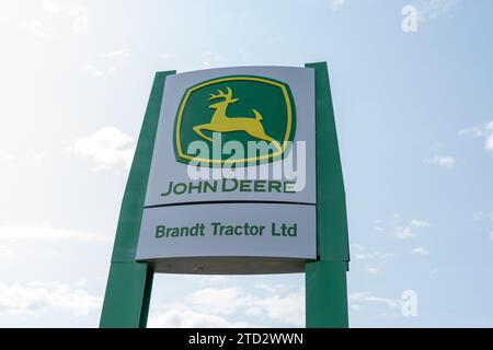 Logo e cartello John Deere e Brandt Tractor Ltd con sfondo blu. Calgary, Alberta, Canada Foto Stock
