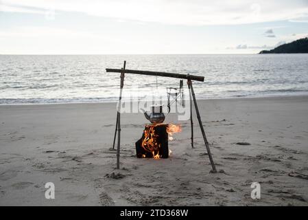 bollitore d'acqua bollente sul fuoco di legno vicino alla spiaggia. Foto Stock