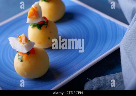 Tipico cibo peruviano chiamato causa, presentato sotto forma di palle su sfondo blu. Foto Stock