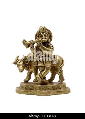 statua vintage del signore krishna che suona musica flauto accanto a una mucca, un avatar vishnu isolato in uno sfondo bianco Foto Stock