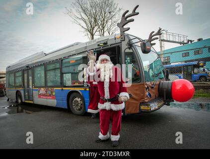 (231216) -- VANCOUVER, 16 dicembre 2023 (Xinhua) -- Un membro dello staff della compagnia di autobus vestito come Babbo Natale posa di fronte a un autobus decorato durante l'evento Toys for Tots a Vancouver, British Columbia, Canada, 15 dicembre 2023. (Foto di Liang Sen/Xinhua) Foto Stock