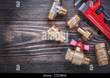 Assortimento di chiavi per scimmia regolabili, raccordi in ottone, valvola dell'acqua su legno, concetto idraulico Foto Stock