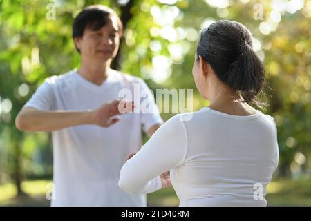 Coppia anziana asiatica che fa esercizi Qigong nel parco. Concetto di stile di vita sano. Foto Stock