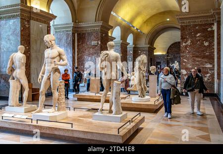 Gente che cammina attraverso le statue greche in mostra presso la Galerie des Antiques nell'ala Sully del Museo del Louvre a Parigi, in Francia Foto Stock