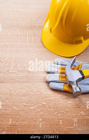 Elmetto giallo guanto di protezione martello a griffe su tavola di legno concetto di costruzione Foto Stock