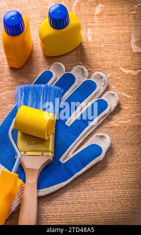 Rullo per pittura, biberon a spazzola e guanti protettivi su tavola di legno Foto Stock